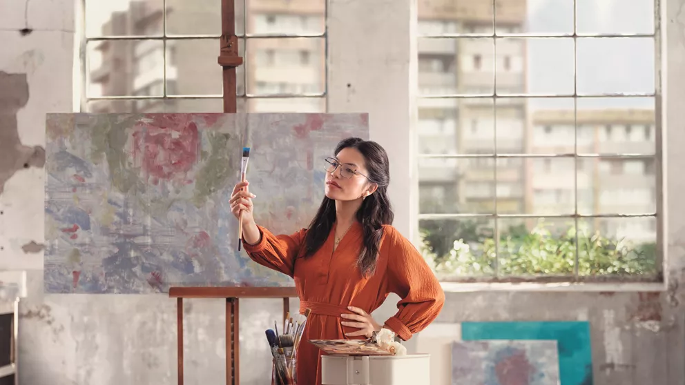 Female artist looking at paintbrush while wearing HOYA Sensity Shine lenses