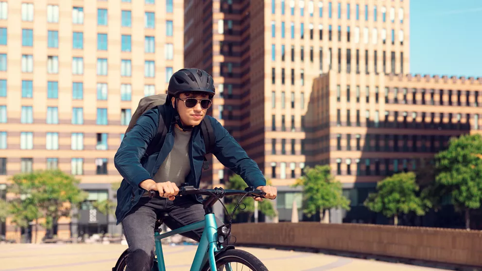 Man riding mountainbike in the city wearing helmet and HOYA Sensity Fast sunglasses