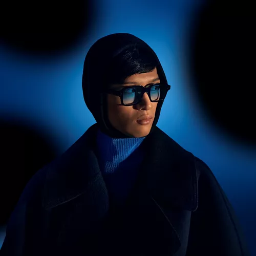 Man with blue tinted sunglasses in front of a dark blue background